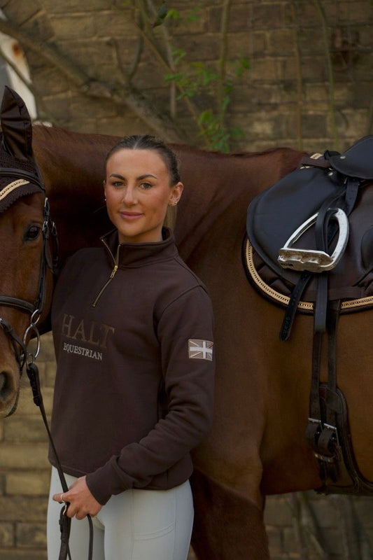 Rider wearing a HALT Chocolate half zip beside a horse